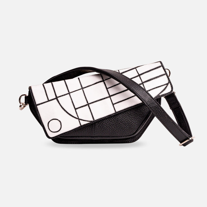 Black and white leather crossbody bag with geometric pattern flap and adjustable strap