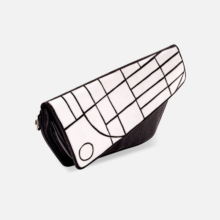 Black and white geometric patterned leather clutch purse with flap closure on white background