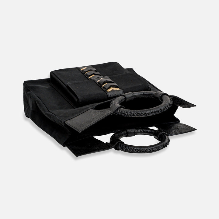 Black fabric tote bag with braided round leather handles and a folded pouch on top