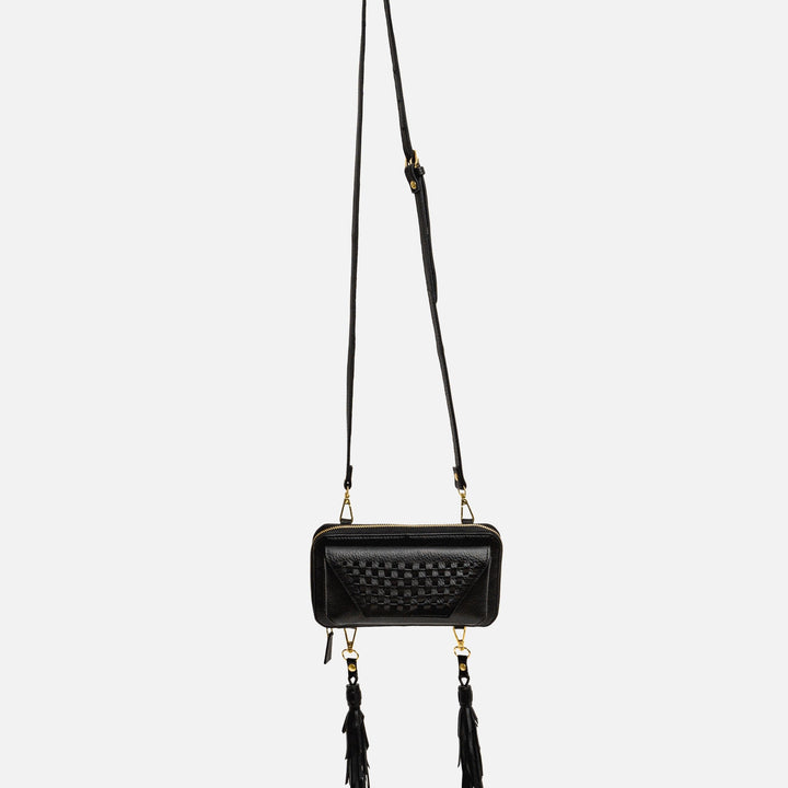 Black leather crossbody bag with woven front detail and two long tassels on white background