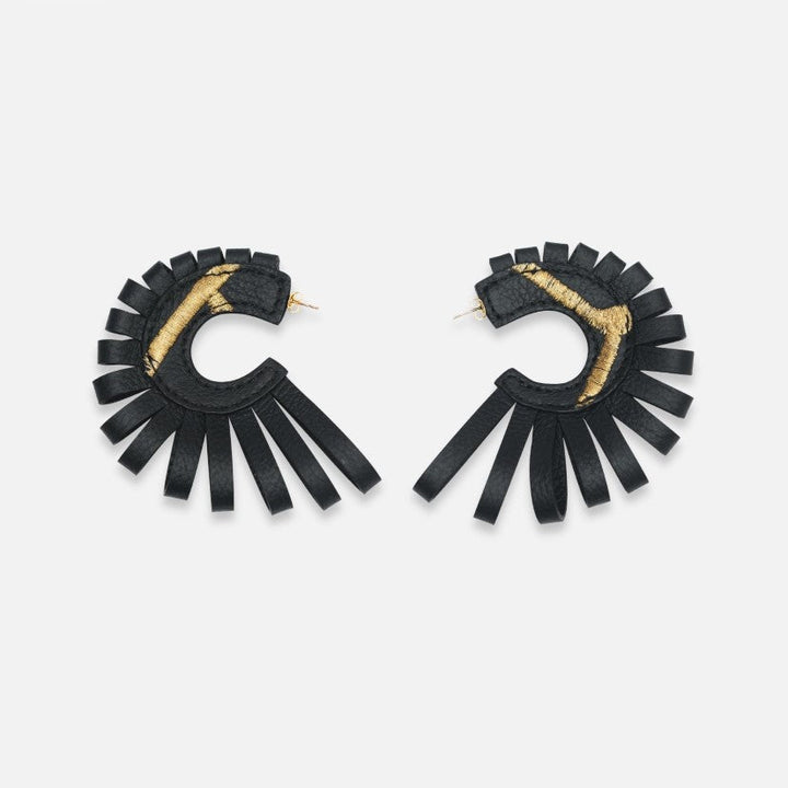 Pair of black leather hoop earrings with gold thread detail and fringe design on white background