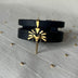 Timeless black leather wrap bracelet with gold lion head pendant on light fabric surface with small gold beads