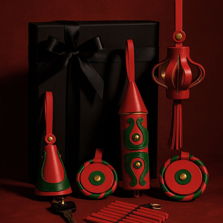 Elegant black gift box with black ribbon alongside red and green leather keychains and decorations on red background