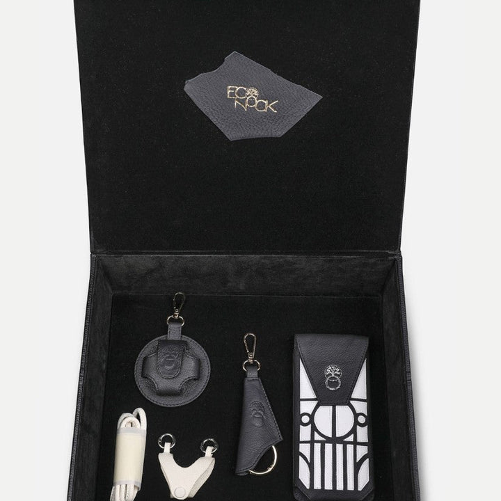 Open black leather gift box with upcycled handcrafted accessories including keychains and a pouch