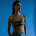 Model wearing a timeless tan leather upcycled waistbelt with golden embroidery and high-waisted blue pants against a blue background