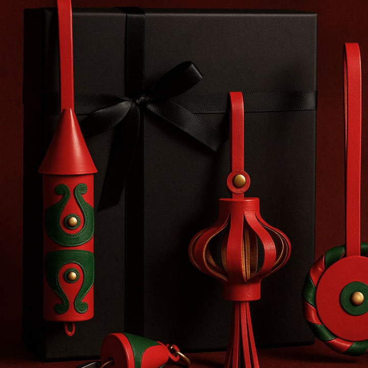 Black gift box with black ribbon, decorated with red and green leather keychains and ornaments