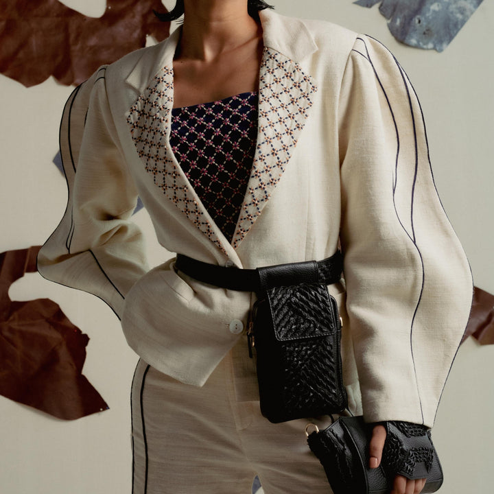 Fashionable woman in white suit with puffy sleeves, embroidered collar, black belt bag and clutch