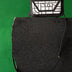 Black and white geometric-patterned leather crossbody bag on black stone with green background