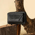 Black textured leather wallet with woven detail on rustic wood and sand background