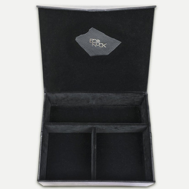 Open black velvet organizer box with three compartments and logo patch inside the lid