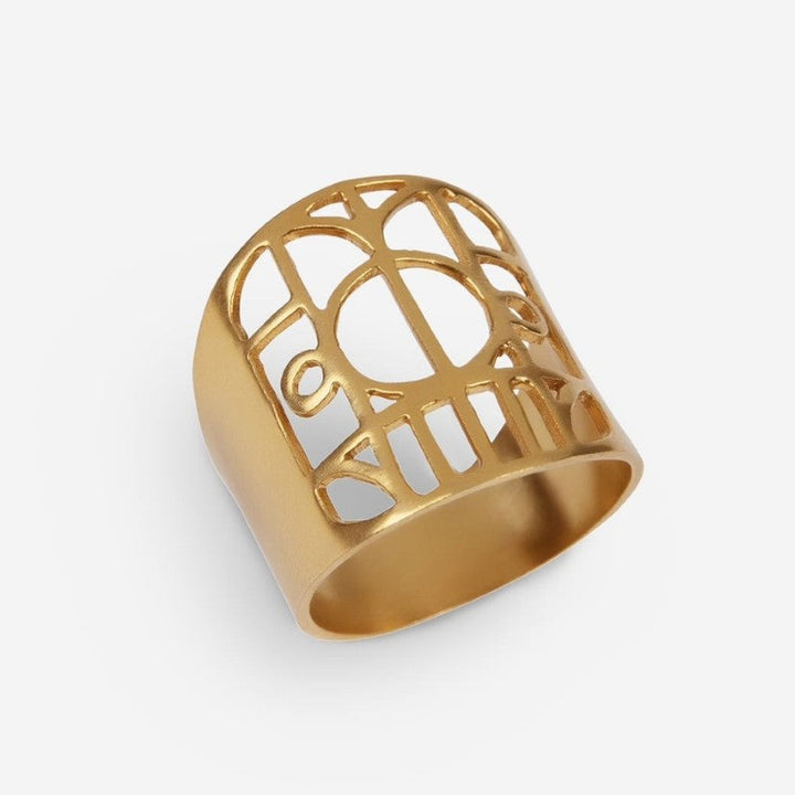 Gold metal ring with intricate geometric cutout pattern on white background