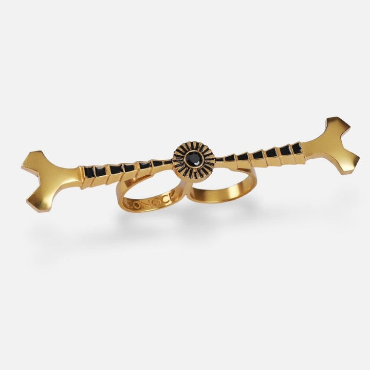 gold-tone metal double finger ring with black enamel detailing and stud accents on white background
