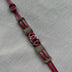 Handmade leather bracelet with burgundy straps and metal rings on gray fabric background