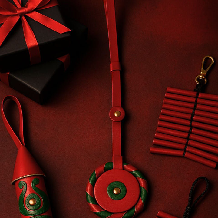 Red and green leather keychains with black gift boxes tied with red ribbons on dark red background