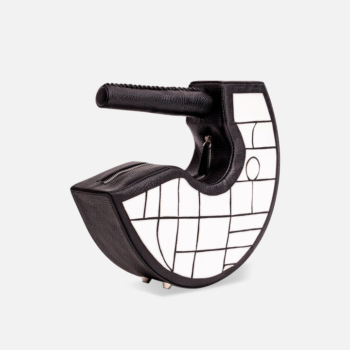 Black and white half-moon shaped leather handbag with geometric pattern and round handle