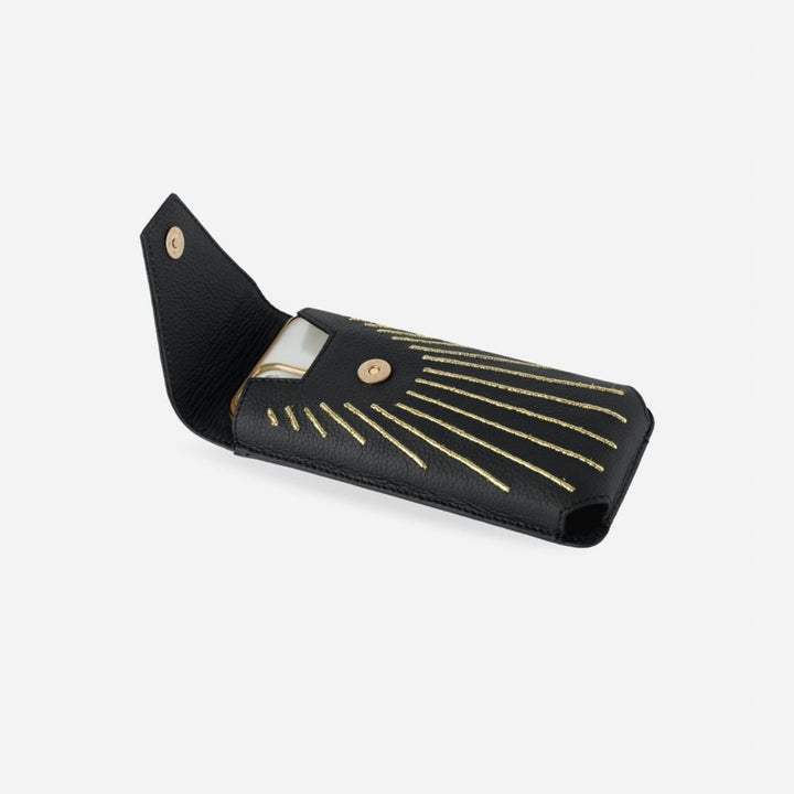 Black leather phone sling with gold embroidered rays and magnetic closure, holding a smartphone