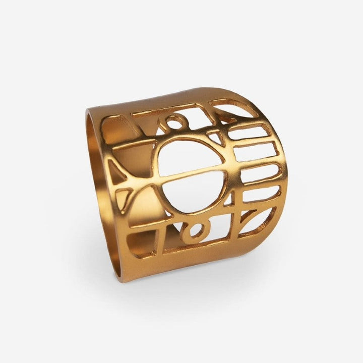Gold-tone metal ring with cut-out geometric and circle design on white background
