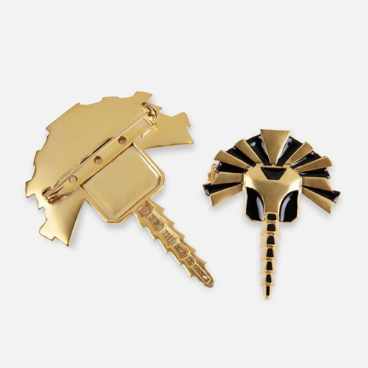 Gold and black enamel metal brooch with pin fastening, handcrafted design resembling a stylized insect or bird