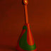 Red and green leather bag charm with gold button on red background