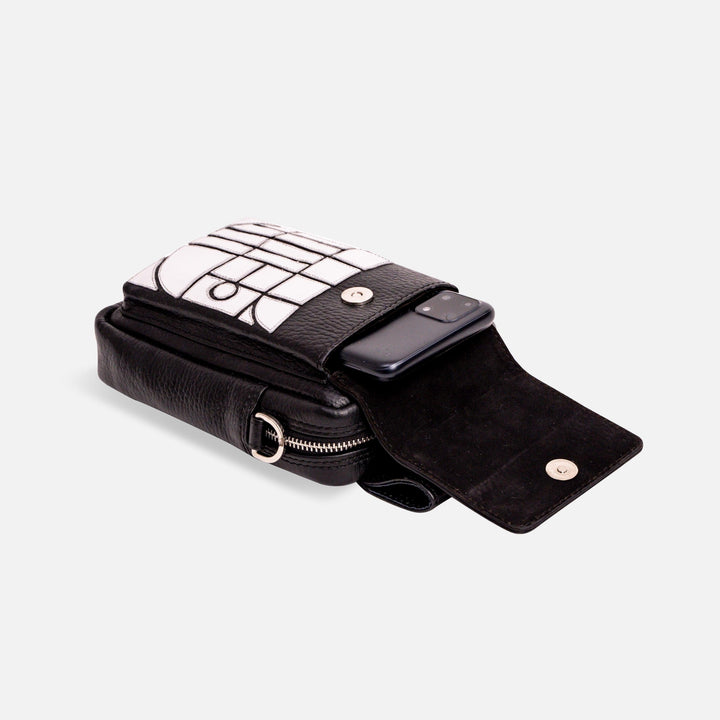 Black leather crossbody bag with white geometric flap and smartphone inside, isolated on white