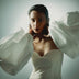 Woman wearing white corset top with large puffed sleeves and geometric gold necklace