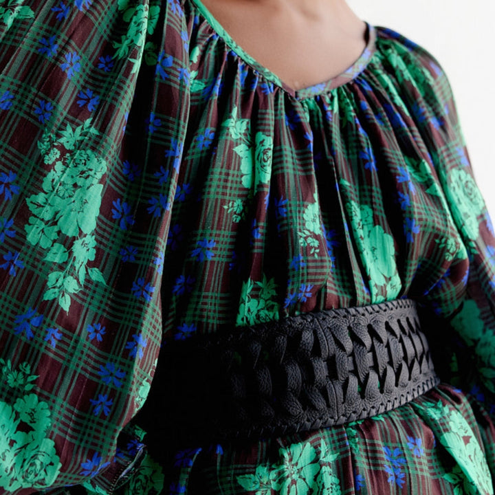 Close-up of person wearing green and blue floral plaid blouse with puff sleeves and black woven belt