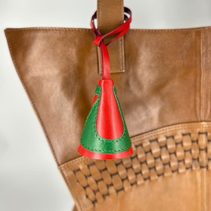 Red and green leather charm attached to brown woven leather handbag strap