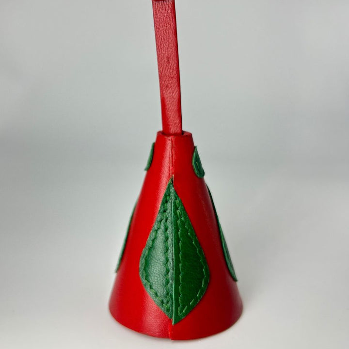Red leather bell-shaped charm with green leaf applique and gold button on strap