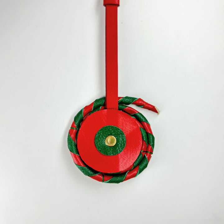 Red and green leather chakri charm with gold accent on white background