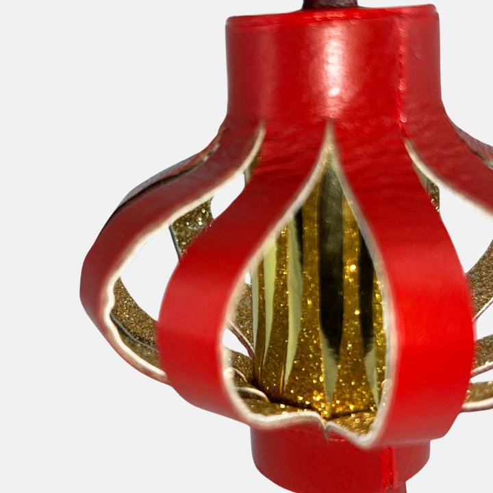 Close-up of red decorative Chinese lantern with gold glitter details on white background