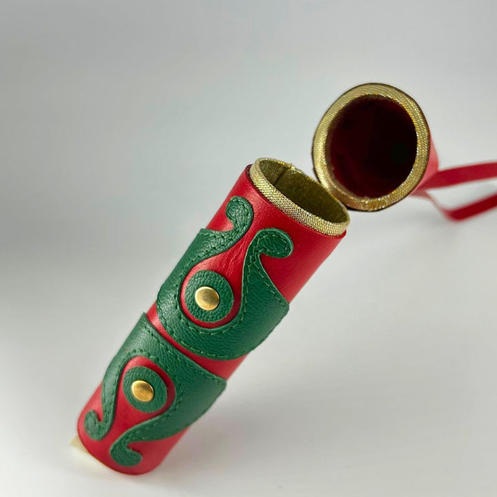 Red and green leather cylindrical case with gold button details and a gold-rimmed open lid